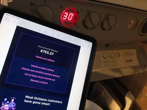 An iPad tablet with Octopus monthly costs, near a central heating boiler