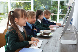 Students working on tablets and desktop computers in classroom