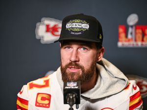 Travis Kelce speaking into a microphone