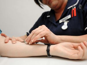 A nurse takes blood during a blood test at a doctor's surgery