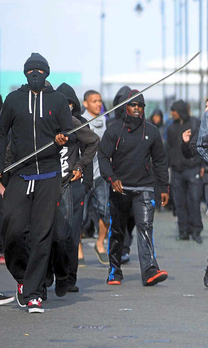 One rioter with his face hidden carries a weapon in the street