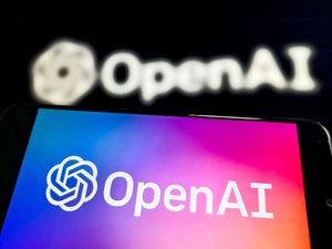 OpenAI logo on a phone in front of a company sign