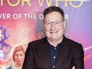 Chris Chibnall smiling, with Doctor Who signage behind him