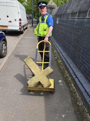 A PCSO officer is pictured transporting the cross back to the church