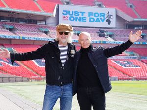 Bob Geldof and Midge Ure on the pitch at Wembley with a Just For One Day promotional sign behind