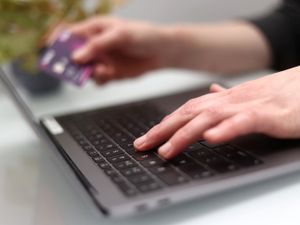 A woman using a laptop as she holds a bank card