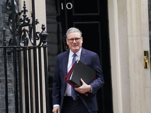 Sir Keir Starmer walking out the door of 10 Downing Street carrying folders under his left arm