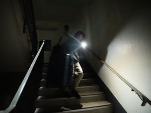 A person walks down unlit stairs using a phone as a torch