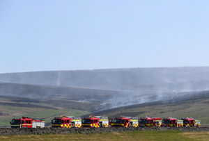 Fire engines lined up as smoke rises from the moor