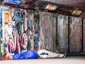 Rough sleepers in a graffitied tunnel walkway