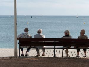 Rear view of four older people sitting on a bench