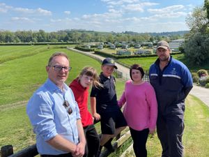 From left to right: Russell George MS, Frankie, Dougie, Sam and Ed Williams. The proposed route would be visible in the background from left to right, behind the holiday homes. Photo: Russell George MS
