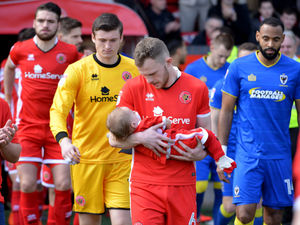 Player Nicky Devlin walking onto the pitch with one-year-old Teddie Phillips in April 2018. 
