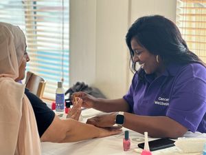 A volunteer paints ladies' nails at the Cancer Wellbeing Fair