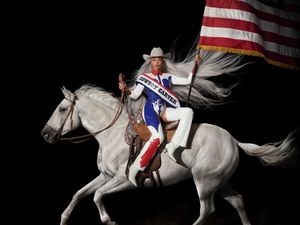 Beyonce on a grey horse holding an American flag