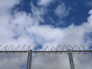 A prison fence with blue sky behind