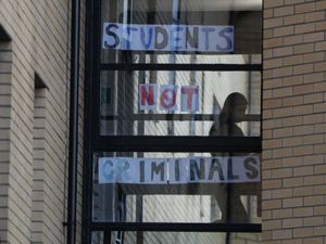 Posters on a window reading 'Students not criminals'