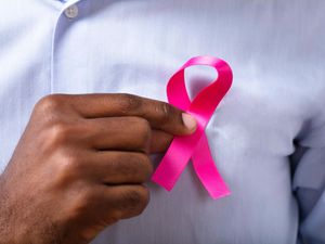 Man's hand with pink ribbon supporting breast cancer cause