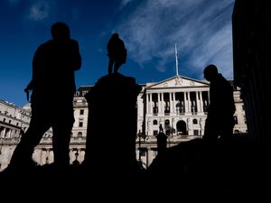 Silhouettes of people walking in front of the Bank of England