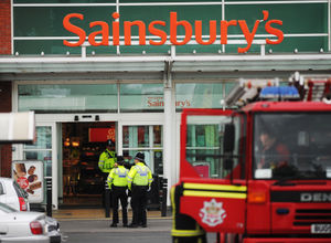 A fire engine parked directly outside the front of the supermarket