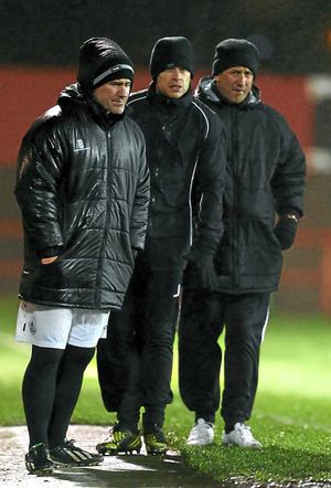 Dominic Morley the assistant manager of AFC Telford United, Alan Mogan player coach and Liam Watson the manager of AFC Telford United watch on in the torrential rain