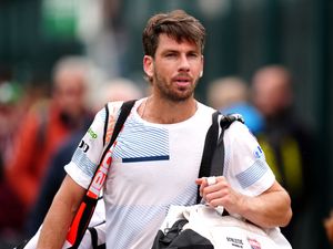 Cameron Norrie looks on as he carries his tennis bags