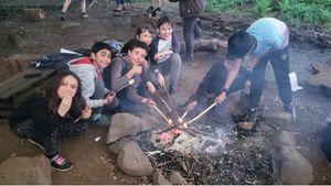 Young people enjoying toasting marshmallows around a campfire