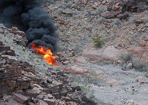 A survivor, lower right, walks away from the scene of a deadly tour helicopter crash along the jagged rocks of the Grand Canyon, in Arizona