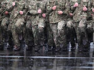 A line of soldiers marching but with their heads not shown in the picture