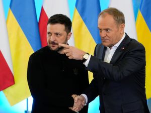 Donald Tusk points as he shakes hands with Volodymyr Zelensky