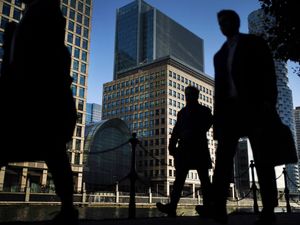 Office workers and commuters walk through Canary Wharf in London