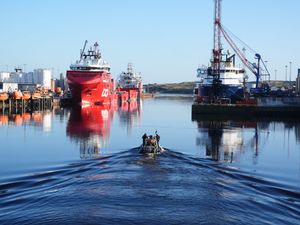 Police boat in harbour water, with ships in the background