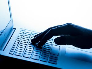 A woman’s hand pressing keys of a laptop keyboard