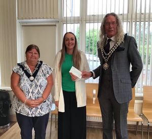 Emily from Llandrindod Wells Children’s Eisteddfod receives their cheque from Llandrindod Wells Mayor Councillor Steve Deeks-D'Silva watched by Deputy Mayor Councillor Kim Nicholls