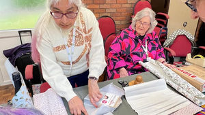 Meena Khiroya demonstrating gift wrapping with President Janis Lomas
