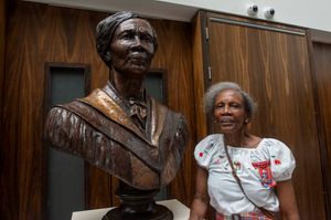 Mel Chevannes CBE with the bust of her which stands in Wolverhampton Art Gallery