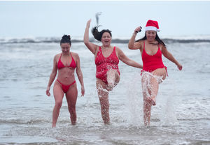 People splashing in the sea on Christmas Eve at Cullercoats Bay in North Tyneside. Forecasters are not predicting a white Christmas but a dry and sunny Christmas Day for most of the UK, although many will wake up to a frosty Christmas Day morning. Photo: Owen Humphreys/PA Wire