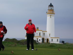 Donald Trump plays golf at Turnberry, with a lighthouse in the background