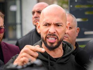 Andrew Tate gestures while speaking to the media