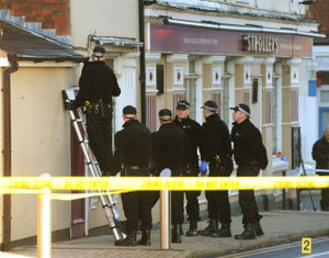 Police officers examine the scene at The Strollers pub, next to where the shooting happened