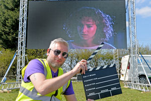 Nick Ricketts poses in front of the giant screen as the drive-in cinema returns to Lower Drayton Farm