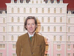Wes Anderson in front of a Grand Budapest Hotel model