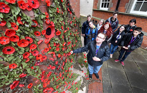 Foundation Studies Creative Arts students next to their poppy display at Stafford College, which were made from plastic bottles. Pictured in the foreground is student Tom Bailey in 2018
