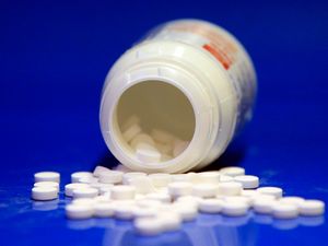 Aspirin tablets in front of an open bottle