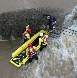Firefighters rescue a motorcyclist trapped on a gate in swirling flood waters. Pic: Ben Lee