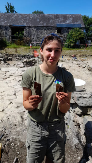 A participant holding a selection of pottery finds in 2025