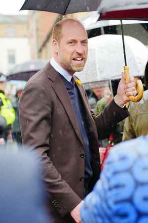 The Prince of Wales shelters from rain under a umbrella whilst meeting members of the public during a visit to the Hanging Gardens. Photo: Ben Birchall/PA Wire