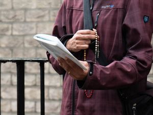 Close-up of hands with rosary beads and a prayer book