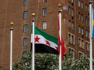 Syria's new flag is raised during a ceremony where it was added to the 100 flags flying in line at United Nations headquarters