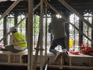 Workers reinstall the stain glass on the 19th century building